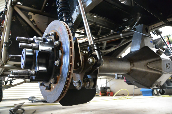A full-floating hub on the end of a Currie 9-Inch axle provides maximum strength for racing. The guard in front of the lower shock ends protects them from anything that gets spit up off the course.